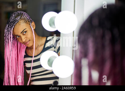 Inhalt junge Frau mit rosa Litzen an ihrem Spiegelbild suchen Stockfoto