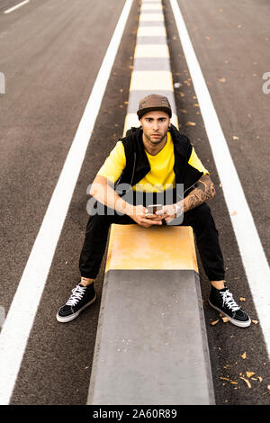 Portrait von tätowierten jungen Mann mit Smartphone im Freien Stockfoto