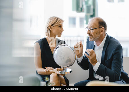 Kaufmann und Frau im Café sitzen, im Globe suchen, Diskussion von Stockfoto