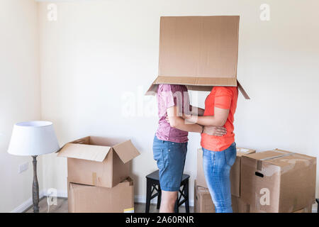 Paar Umzug in neues Zuhause versteckt unter Karton Stockfoto