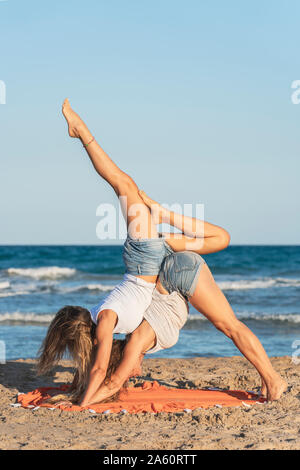 Zwei Frauen praticing Acro Yoga am Strand Stockfoto