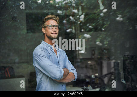 Lässige junge Unternehmer hinter Fensterglas im Büro Stockfoto