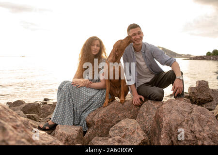 Junges Paar mit Hund am Strand Stockfoto