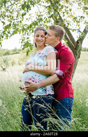Schwangere Frau und Mann baby Holding Bauch, Mann küsste seine Frau Stockfoto