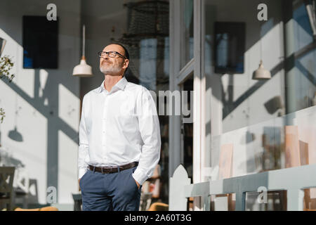 Geschäftsmann stansing vor Coffee Shop, Sonnenschein genießen. Stockfoto