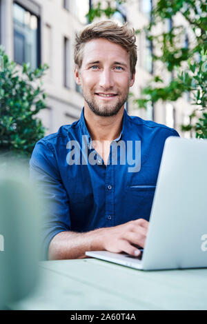 Portrait der junge Unternehmer mit Laptop an einer im Cafe in der Stadt Stockfoto