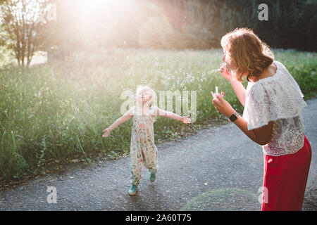 Mutter macht Seifenblasen für ihre kleine Tochter Stockfoto