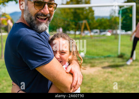 Gerne Vater und Tochter umarmen auf einem Fußballplatz Stockfoto