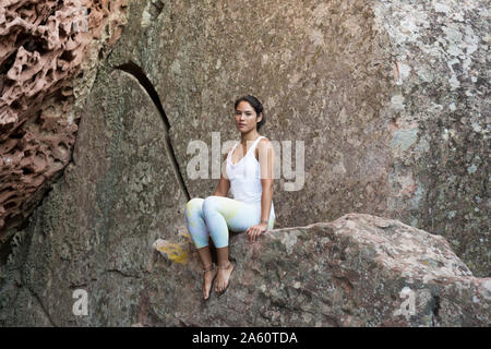 Junge asiatische Frau sitzt auf einem Felsen Stockfoto