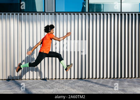 Junge Mann in der Stadt springen, metallische Wand im Hintergrund Stockfoto
