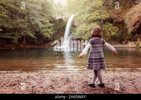 Junge Mädchen stehend an einem Wasserfall Stockfoto