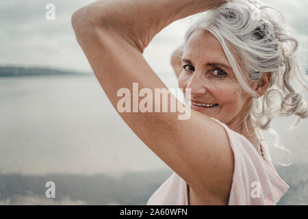 Weiß behaarte ältere Frau, die durch das Meer posing Stockfoto