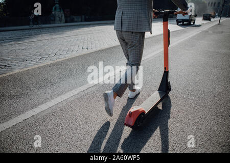 Unternehmer gehen mit e-Scooter in der Stadt Stockfoto