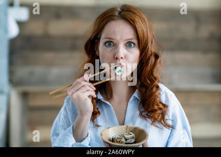 Porträt der rothaarigen Frau isst Sushi Stockfoto