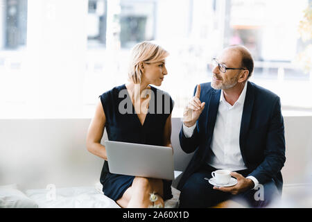 Kaufmann und Frau im Café sitzen, mit Laptop Stockfoto