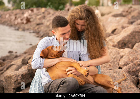 Junges Paar mit Hund am Strand Stockfoto