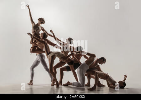 Die Gruppe der modernen Ballett Tänzer. Zeitgenössische Kunst Ballett. Junge flexible athletische Männer und Frauen im Ballett Strumpfhosen. Studio Schuß auf weißem Hintergrund. Negativer Platz. Stockfoto