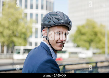 Portrait von lächelnden jungen Geschäftsmann tragen Helm in der Stadt Stockfoto