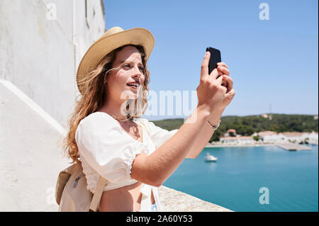 Junge Frau mit einem selfie an der Küste, Menorca, Spanien Stockfoto