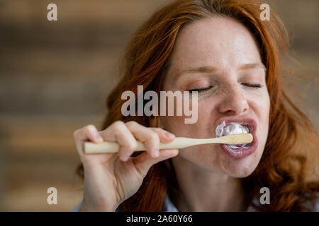 Porträt der rothaarigen Frau, die Zähne putzen