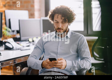 Geschäftsmann mit Handy im Büro Stockfoto