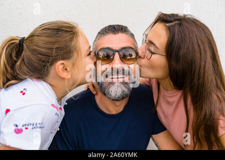 Zwei Töchter küssen glücklich Vater Stockfoto