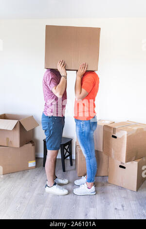 Paar Umzug in neues Zuhause versteckt unter Karton Stockfoto