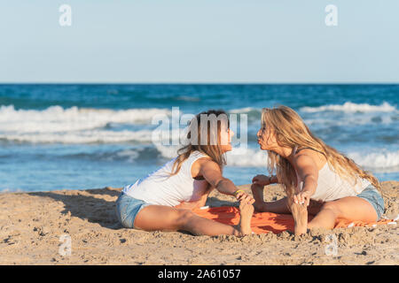 Zwei Frauen praticing Acro Yoga am Strand Stockfoto