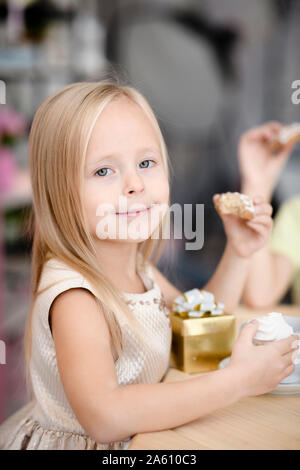 Portrait von lächelnden Mädchen mit Geschenk Box essen Cookies Stockfoto