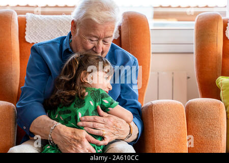 Großmutter ihrer Enkelin umarmen im Wohnzimmer Stockfoto