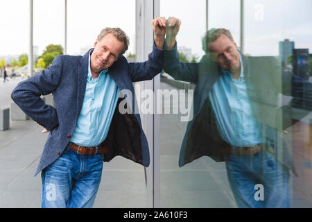 Portrait von zuversichtlich älterer Geschäftsmann lehnte sich gegen Glas vorne Stockfoto