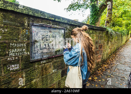 Penny Lane Reflexionen, Liverpool, Großbritannien. Der Straße, die in der berühmten Beatles Song. Eine Frau nimmt ein Foto von der ikonischen Zeichen. Stockfoto