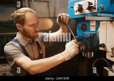 Junge Bartgeier Techniker der Hebel und steuert die Drehmaschine in der Anlage Stockfoto