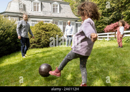 Glückliche Familie Fußball spielen im Garten Stockfoto