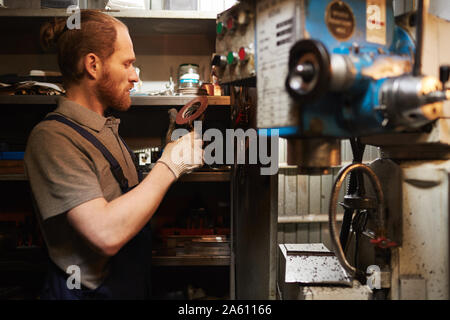 Junge Bartgeier Mechaniker Prüfung metall Details während der Arbeit im Lager Stockfoto