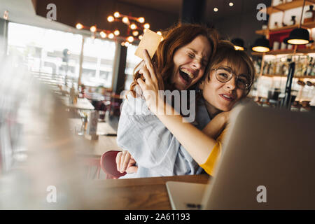 Zwei aufgeregt weibliche Freunde mit Laptop und Kreditkarte in einem Cafe Stockfoto