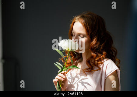 Porträt der rothaarigen Frau duftende weiße Pfingstrose Stockfoto