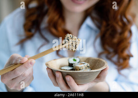 Woman's Hände, die Schüssel und Essstäbchen mit Sushi, close-up Stockfoto