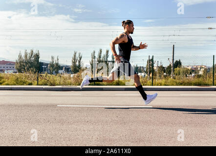 Sportlichen jungen Mann laufen auf einer Straße Stockfoto