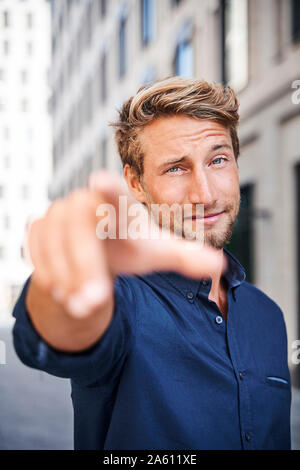 Portrait von selbstbewussten jungen Mann in der Stadt nach seinen Finger Stockfoto