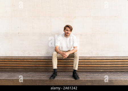 Portrait von lächelnden Mann sitzt auf holzbank Stockfoto