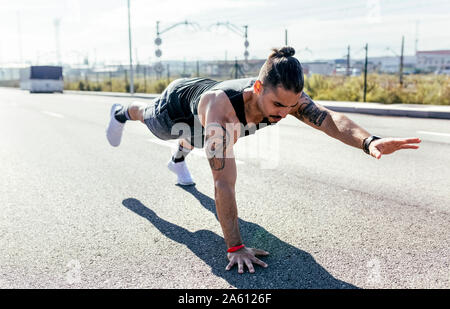Junger Mann tun balance Übung auf einer Straße Stockfoto