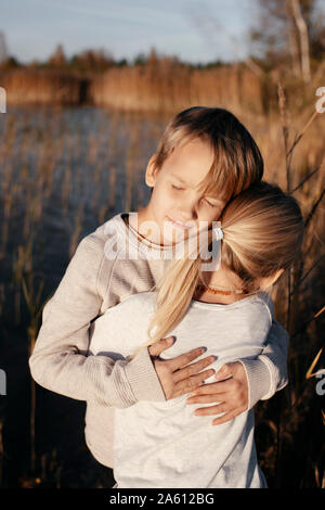 Portrait der Boy seine kleine Schwester umarmen in der herbstlichen Natur Stockfoto