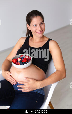 Junge schwangere Frau ist Essen verschiedene Arten von frischem Obst Stockfoto