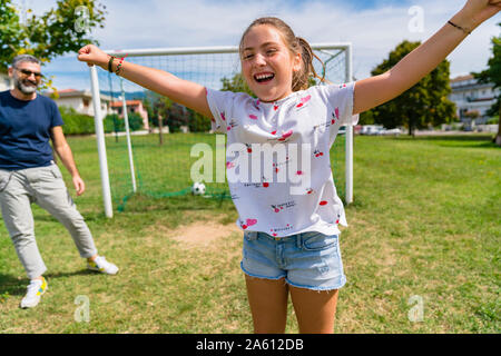 Glückliches Mädchen spielen Fußball mit Vater auf einer Wiese Stockfoto