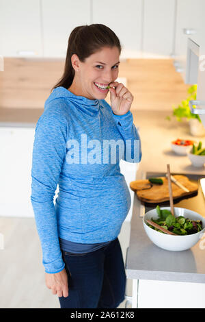 Schwangere Frau vorbereiten frischer Salat in der Küche Stockfoto