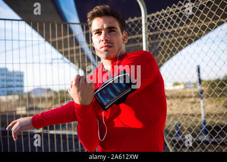 Jogger mit Smartphone im Arm pocket, Stretching seinen Arm Stockfoto