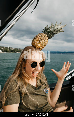Schreien, junge Frau auf einem Boot Ausgleichen einer Ananas auf den Kopf Stockfoto
