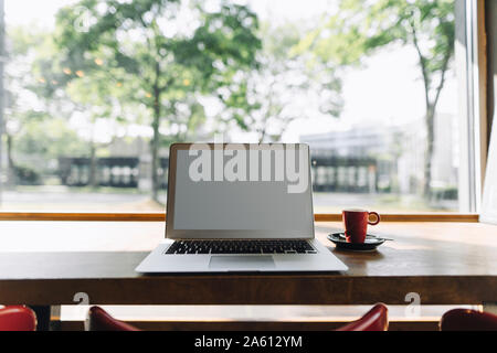 Laptop und eine Tasse Kaffee in einem Café auf Tisch Stockfoto