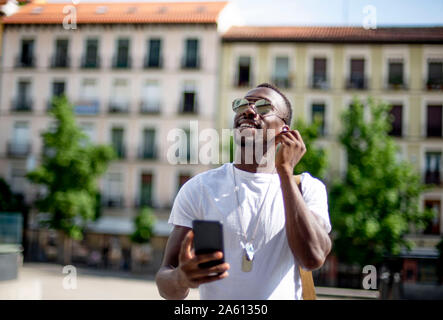 Lächelnden jungen Mann mit Smartphone und Kopfhörer, Stockfoto